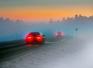 Rear lights of car on road in dark foggy winter evening